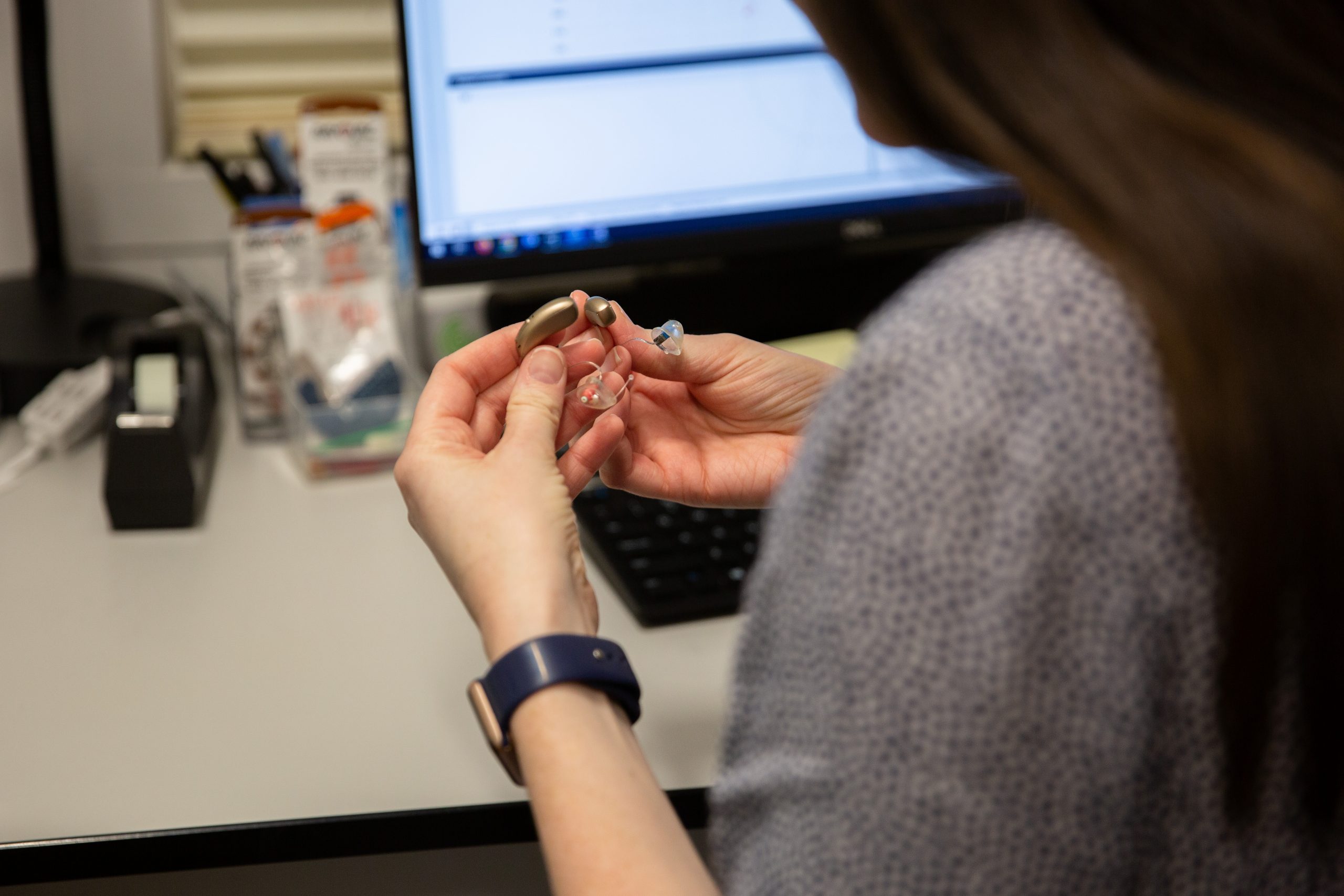 an audiologist holds a hearing aid in her hands